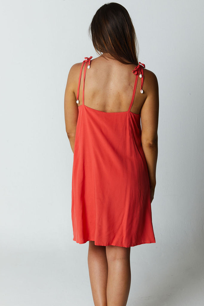 red short romper with tie shoulders with cowrie shell beads on the ends and a detailed texture in the front